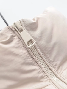 Detailed macro view of the smooth zipper and fabric texture on a beige vest