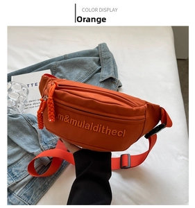 Macro detail of orange canvas chest bag with embossed lettering and woven zipper puller
