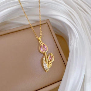 Close-up of gold tulip pendant featuring pink gemstones and pave crystal petals