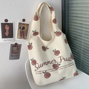 Detail of a beige canvas tote bag featuring a peach print hanging in a bright room