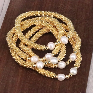 Macro view of multi-strand gold bead bracelet with white irregular freshwater pearls
