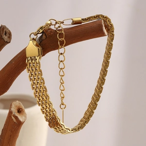 Detailed view of gold mesh chain bracelet hanging on a branch with lobster clasp detail