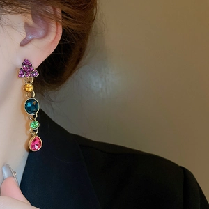 Close-up of golden floral earrings with colorful gemstones and pearls on a model