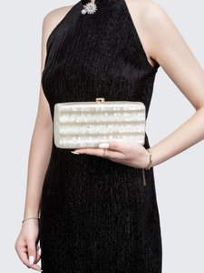 Detail of white marble acrylic evening clutch with metal clasp and mother-of-pearl texture