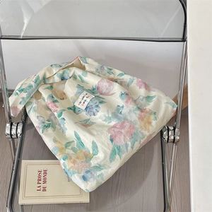 Detailed shot of linen shoulder bag with floral print and woven label on a chair