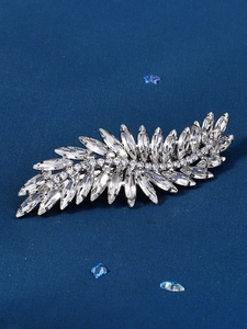Macro shot of leaf-shaped rhinestone hair clip with sparkling crystals on dark blue background