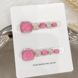 Pink glitter press-on toenails with rhinestone and pearl accents on a display card