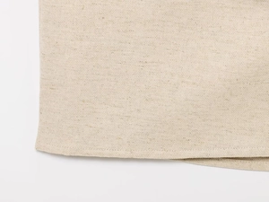 Vista macro del tessuto misto lino beige con bordi rifiniti e cuciture dettagliate