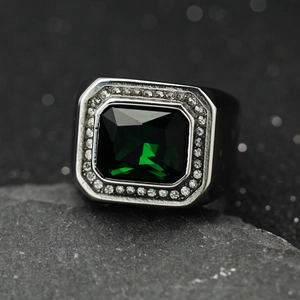 Macro di un anello con gemma verde taglio smeraldo e halo di diamanti su fascia larga