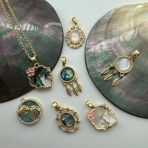 Close-up of 18K gold plated shell charms featuring cat and dreamcatcher designs