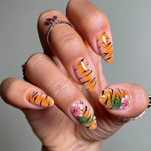 Detail of almond-shaped fake nails featuring tiger print patterns and 3D floral accents