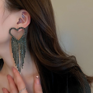 Exaggerated black rhinestone heart tassel drop earrings worn by a model in close-up