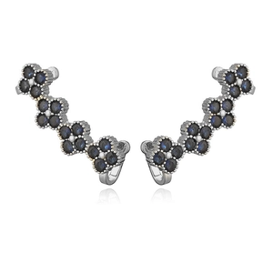 Detailed macro view of silver flower ear climbers with deep blue round-cut crystals