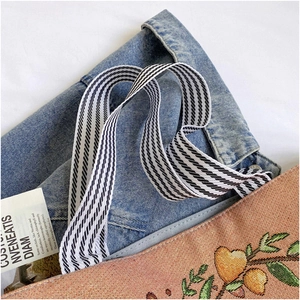 Detailed close-up of woven jacquard tote bag featuring floral embroidery and striped strap