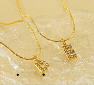 Detailed macro view of 18K gold-plated stainless steel D and E letter pendants on snake chain