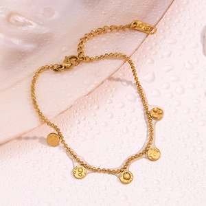 Detailed view of 18K gold beaded chain bracelet with textured coin charms in a seashell