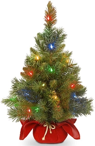 Close-up of a 60cm mini Christmas tree with glowing colorful LED lights and red cloth base