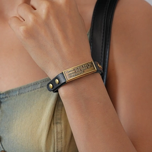 Macro view of vintage leather bracelet featuring engraved metal plate and gold rivets