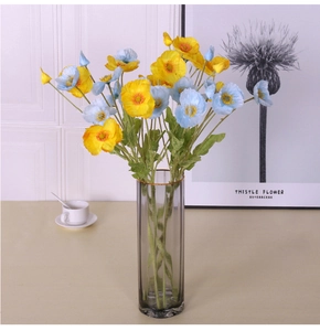 Artificial yellow and light blue poppies in a grey glass vase for home decor