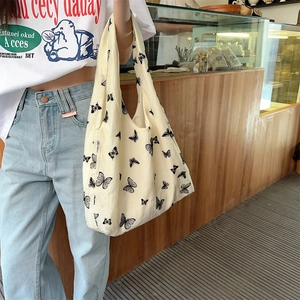 Close-up of the cream canvas tote bag featuring an artistic black butterfly print detail