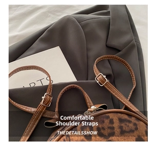 Detail showing adjustable brown leather strap and silver buckle of leopard print backpack