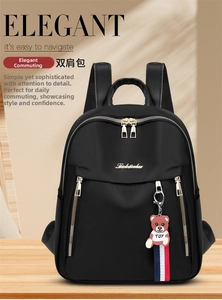 Front view of black nylon backpack featuring gold zippers and a cute bear keychain charm