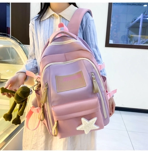 Pink and purple contrast backpack featuring a white star patch and a green frog pendant