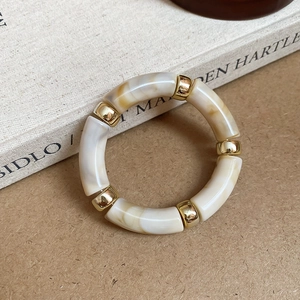 Detail of acrylic marble texture beads and gold metal spacers on an elastic bracelet
