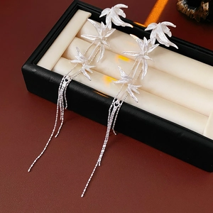 Close-up of silver leaf earrings with long chain tassels inside a black display box