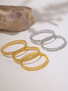 Close-up of gold and silver hollow heart bracelets on stone with natural shadows
