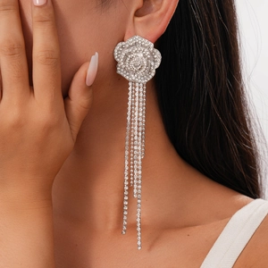 Macro detail of elegant silver floral earrings featuring sparkling crystal tassel chains