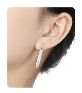 Close-up of minimalist S925 sterling silver sword drop earring worn by a model