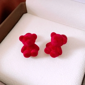 Macro shot of red flocked bear earrings with a velvety texture in a white jewelry box