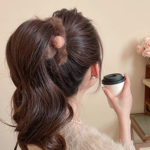 Detailed view of a soft brown faux fur hair scrunchie with pink pompom accessory