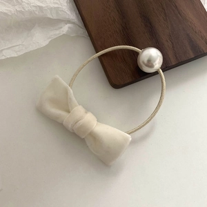 Detail of cream velvet bow hair clip with large white pearl on minimalist elastic band