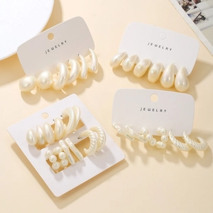 Detail of four sets of elegant cream white acrylic faux pearl earrings in geometric shapes
