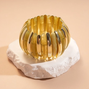Detailed shot of yellow resin and gold metal cylinder beads on an elastic bracelet