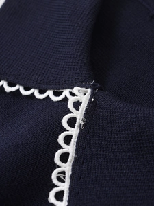 Macro view of navy knit fabric with elegant white scalloped lace edge detail