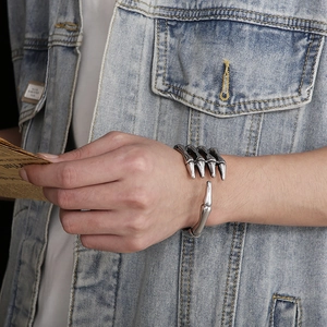 Close-up of vintage silver skull hand cuff bracelet in titanium steel worn by male model