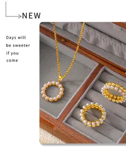 Detail of gold pearl necklace and rings set presented in a premium wooden jewelry box