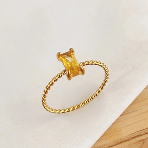 Detail view of a vintage gold rope ring featuring a rectangular yellow gemstone inlay
