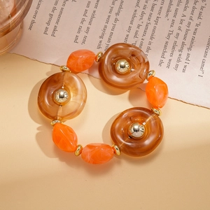 Macro shot of amber resin beads and golden metallic accents on a bohemian sweater necklace