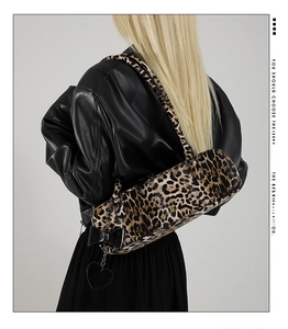 Detailed shot of leopard print cylinder bag with bow and heart chain on leather jacket
