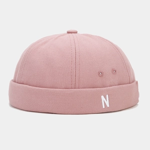 Close-up of pink canvas brimless cap featuring white N embroidery and metal eyelets