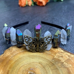 Detail of a handmade bohemian crown with natural crystals and a bronze butterfly on wood