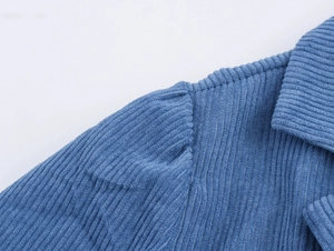 Close-up detail of blue corduroy texture and shoulder seam on a vintage-style midi dress