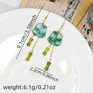Detail view of long tassel earrings with green bamboo charms and precise measurements