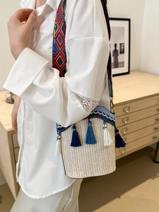 Detail of woven bucket bag featuring bohemian tassels and colorful geometric wide strap