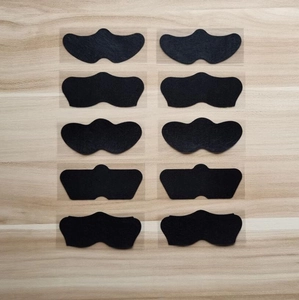 Flat lay of ten black bamboo charcoal nose strips for blackhead removal on wood background