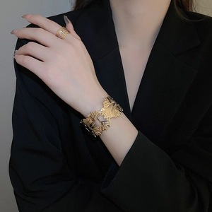 Detail view of gold ginkgo leaf cuff bracelet and matching ring on model with black suit
